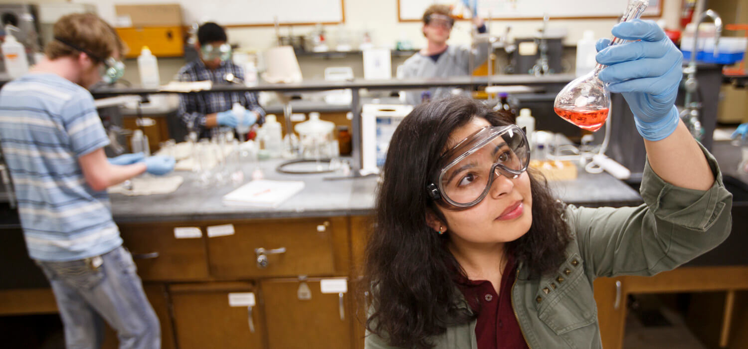 Student with beaker in chemistry lab