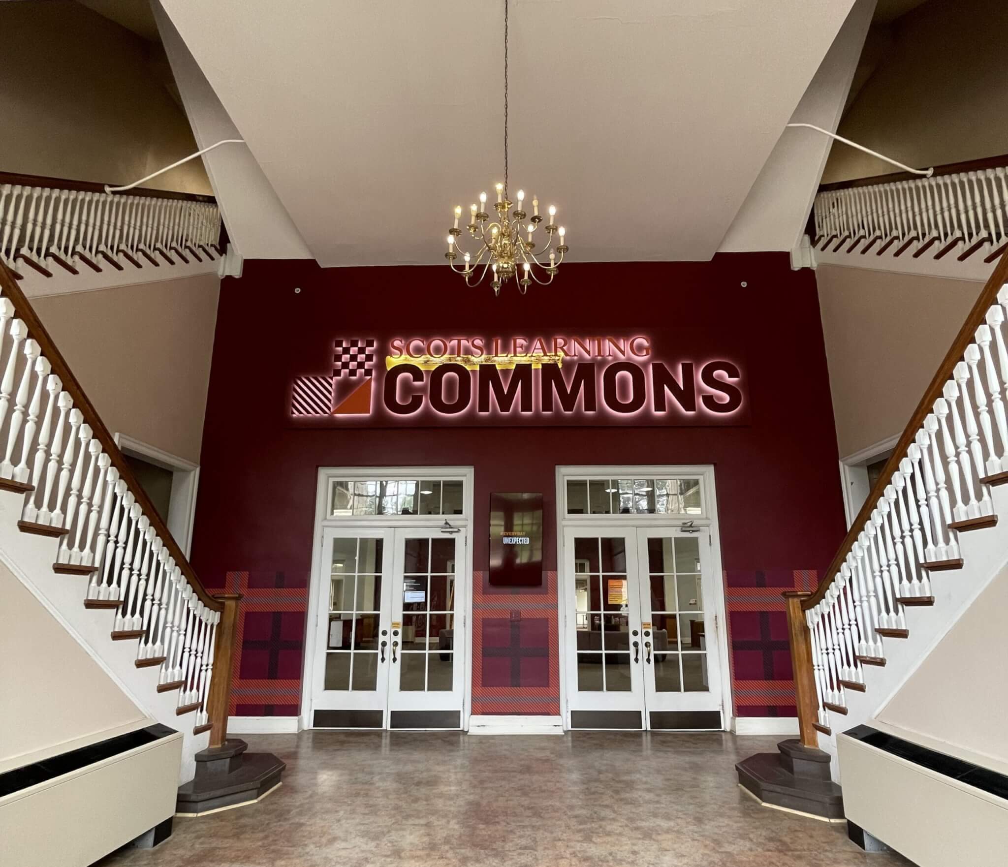 Front entrance to the Scots Learning Commons with a garnet wall and two sets of white double doors.