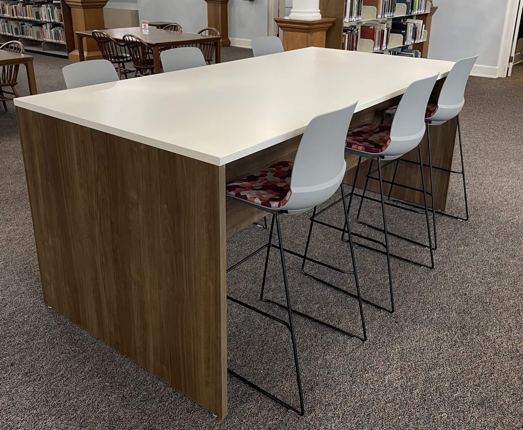 White high-top table with six stools stands in the main study space of the Scots Learning Commons.