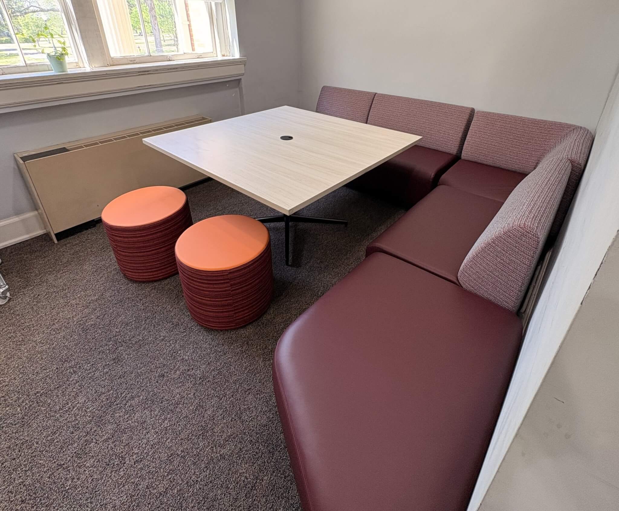 Garnet sectional, orange ottomans, and a large table create a Study Nook in a secluded corner.