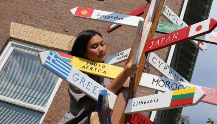 Vietnamese student adding flag board to MC flagpole outside of the International House