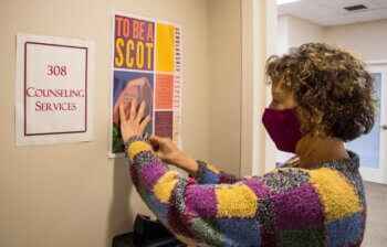 Photo of Claudia Werner hanging Covenant poster