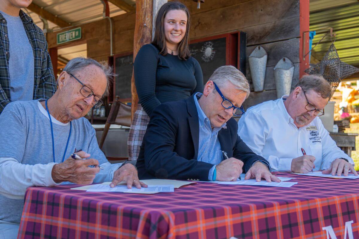 Photo of three men signing papers