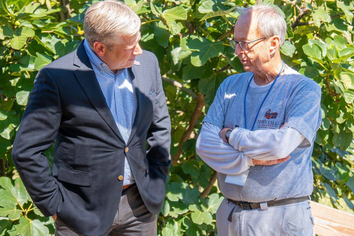 Photo of Dr. Bryan Coker with hands in his pockets, talking to Jim Kirksey with arms crossed