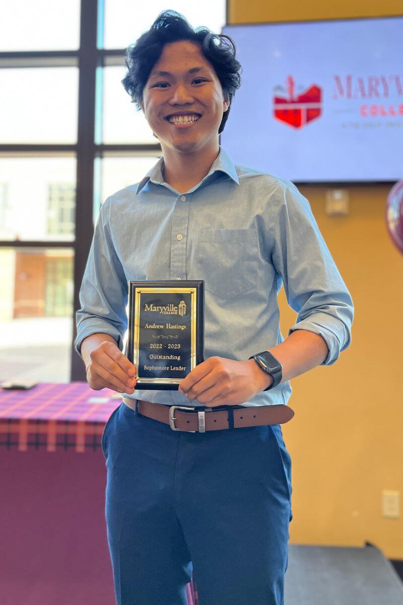 Photo of Andrew Hastings holding a plaque