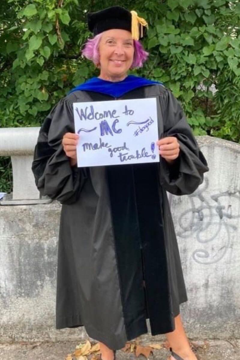 Dr. Rebecca Lucas holding a sign at Commencement 2022.