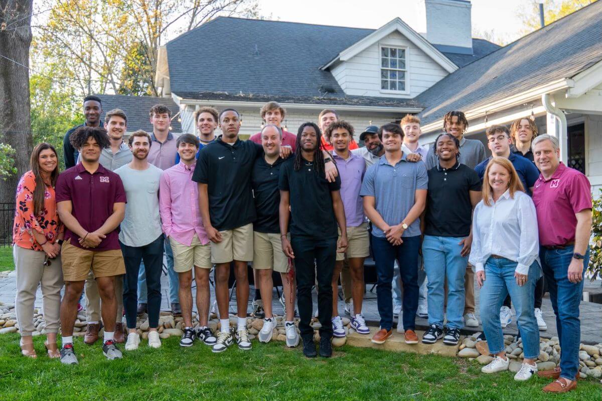 Photo of Dr. Bryan and Sarah Coker with the Maryville College men's basketball team.