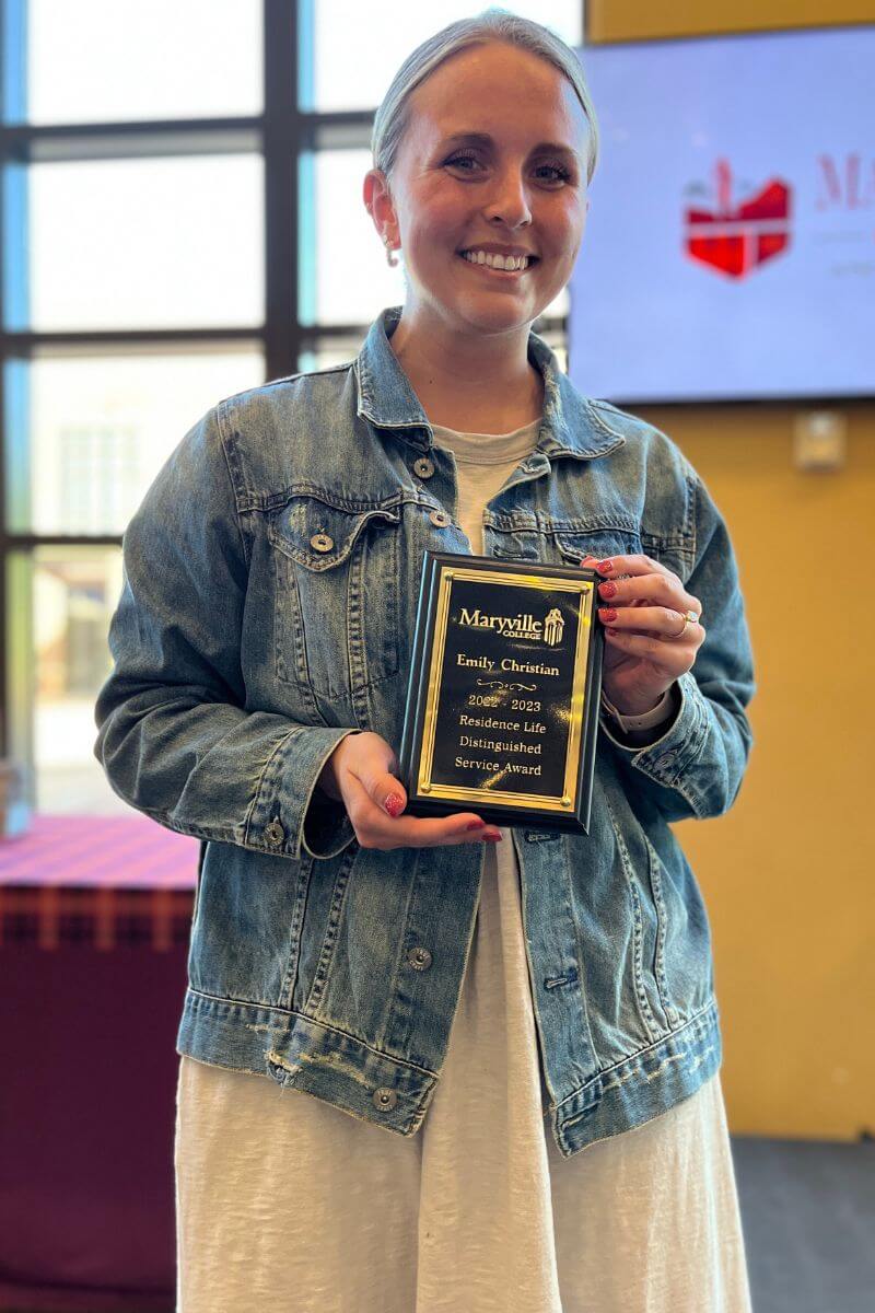 Photo of Emily Jo Christian holding a plaque