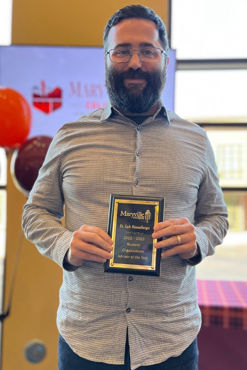 Photo of Dr. Zach Himmelberger holding a plaque