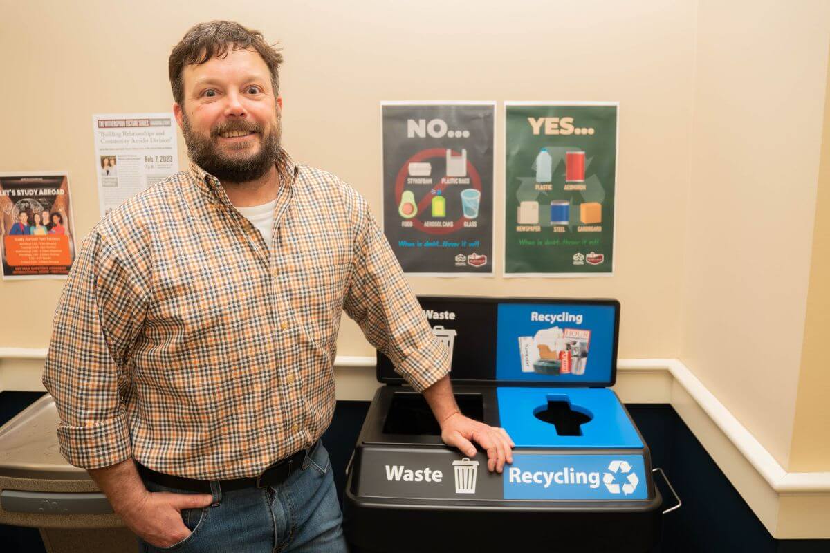 Photo of Dr. Jay Clark standing beside a recycling bin