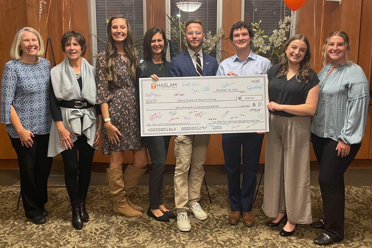 Group of individuals holding a large check at a November presentation