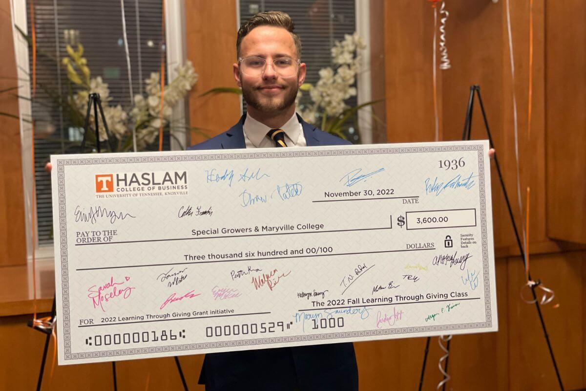 Photo of Kelton Bloxham holding a check