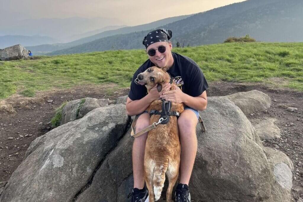 Photo of MC student Grady Cash sitting on a rock with his dog