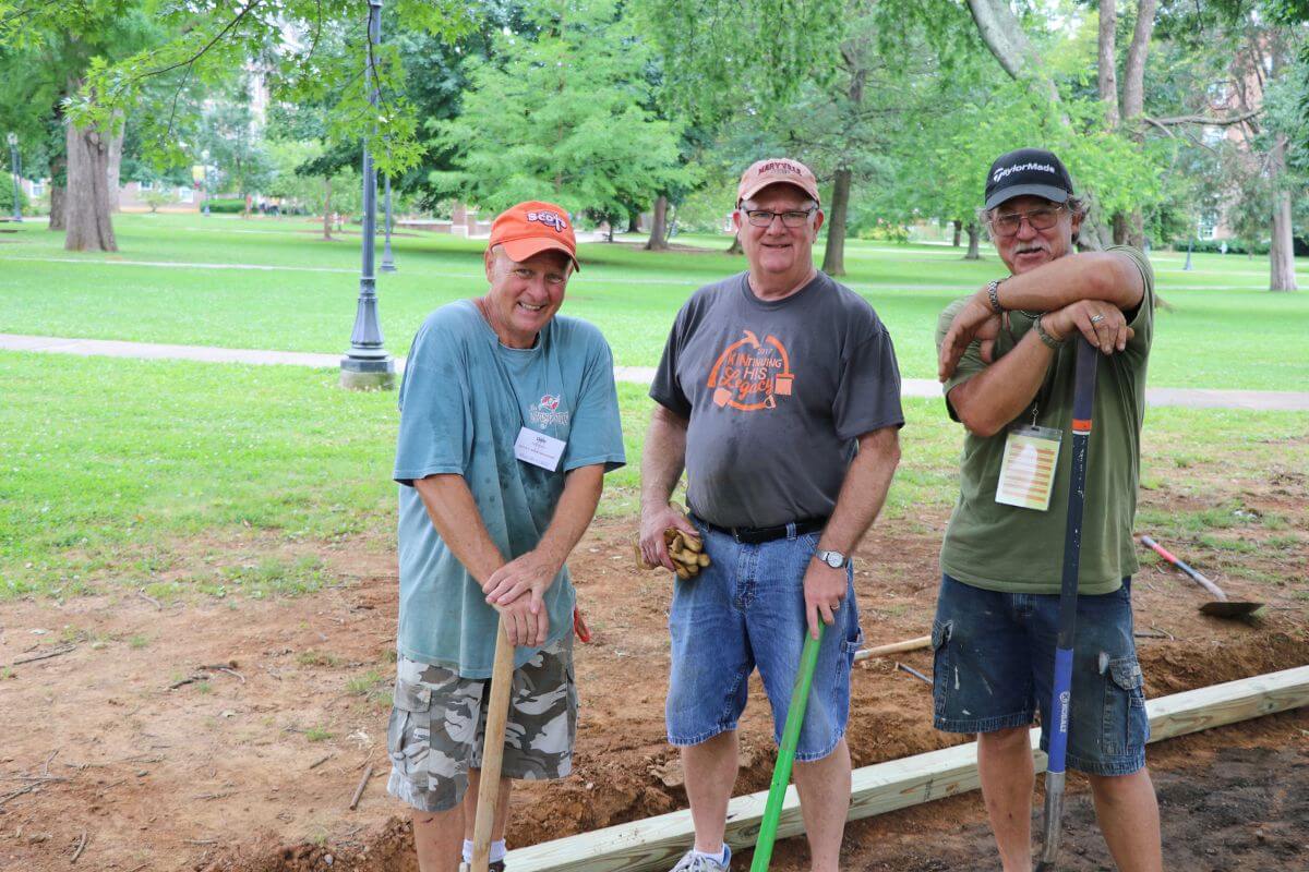 Photo of three men taking a break from digging a ditch