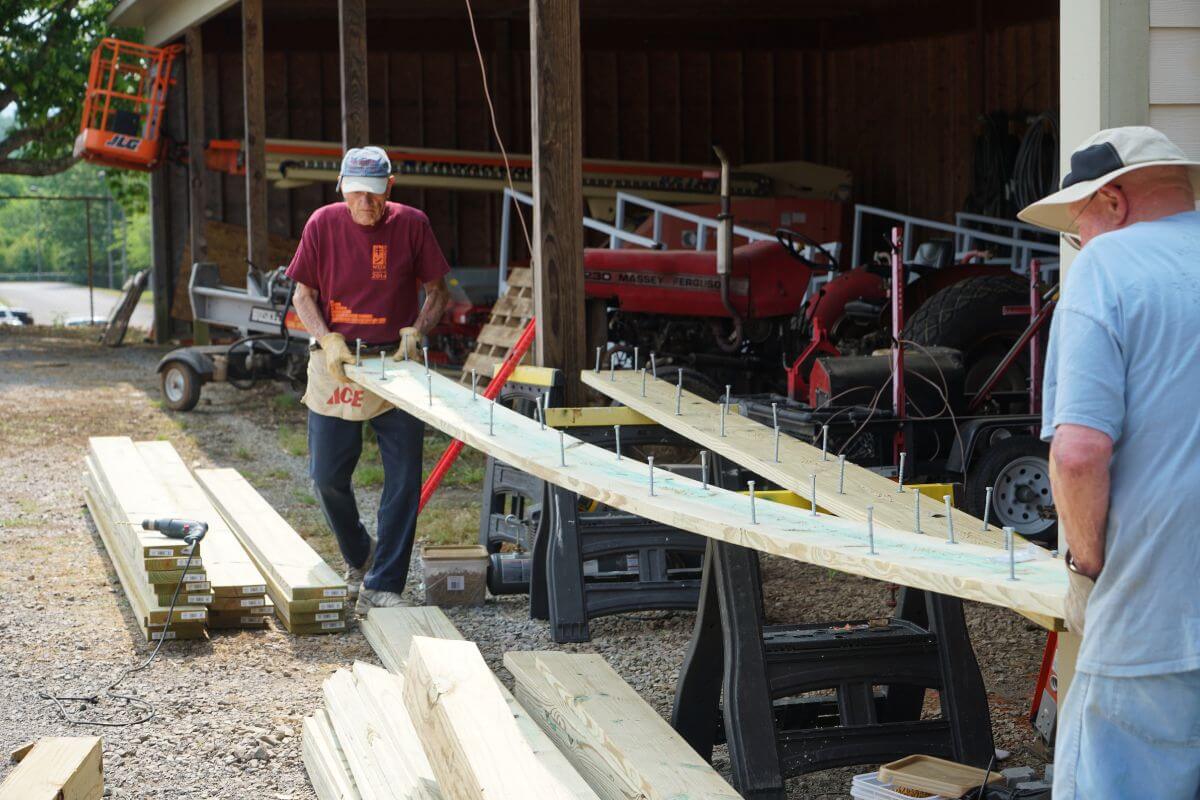 Photo from 2019 KT Days of two men carrying a piece of lumber