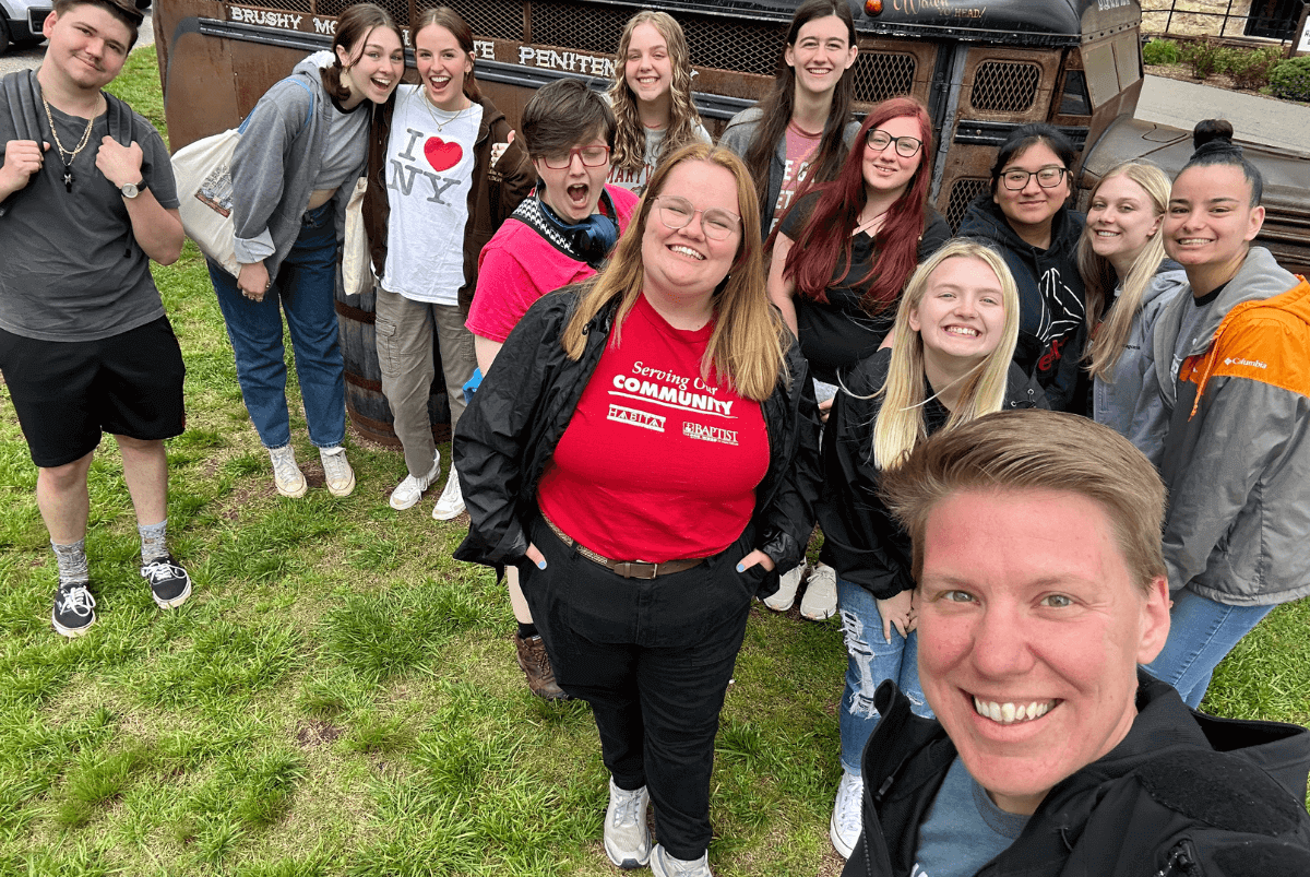 Dr. Rachel Ponder and eleven MC students stand in front of a old bus at Brushy Mountain