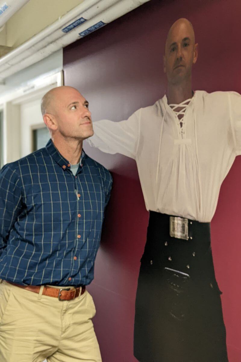 Photo of Noah Bowman looking at a larger-than-life wall photo of himself.