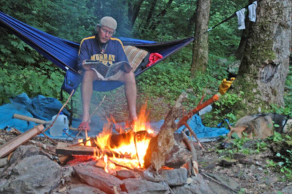 Photo of Kim Trevathan writing in a journal beside a campfire