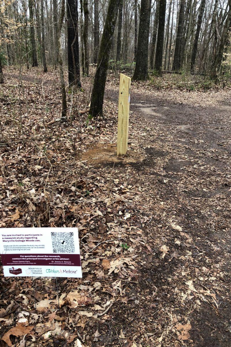 Photo of sign along a MC Woods trail and a six-by-six post with a monitor