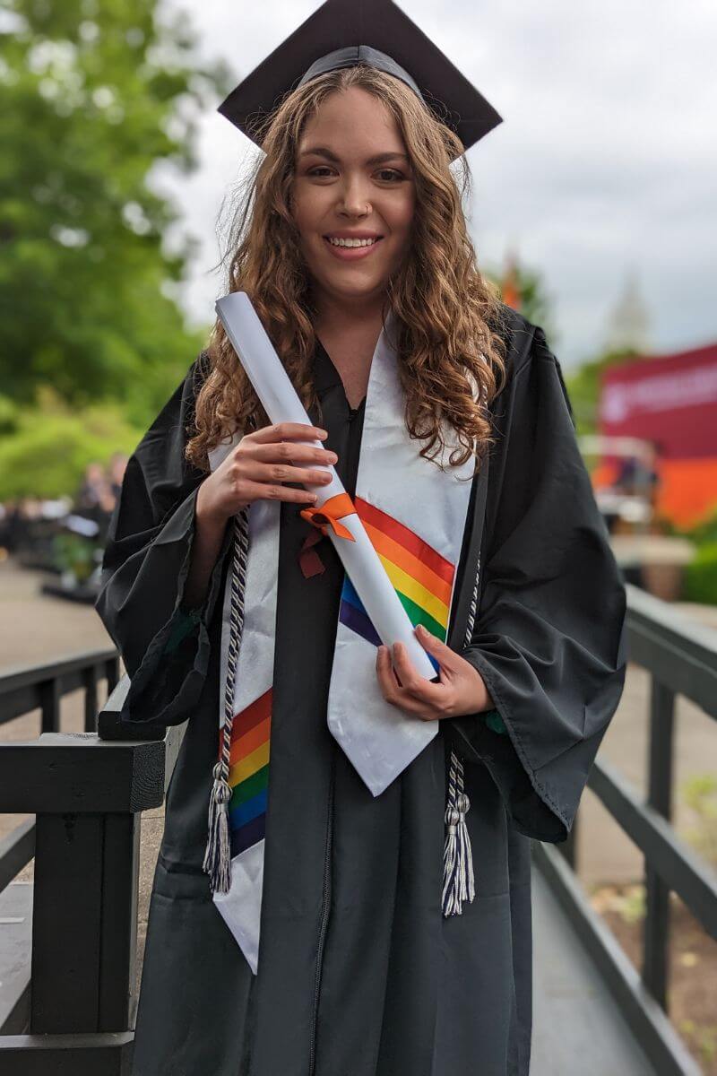 Photo of Ava Bernardino smiling and holding her diploma