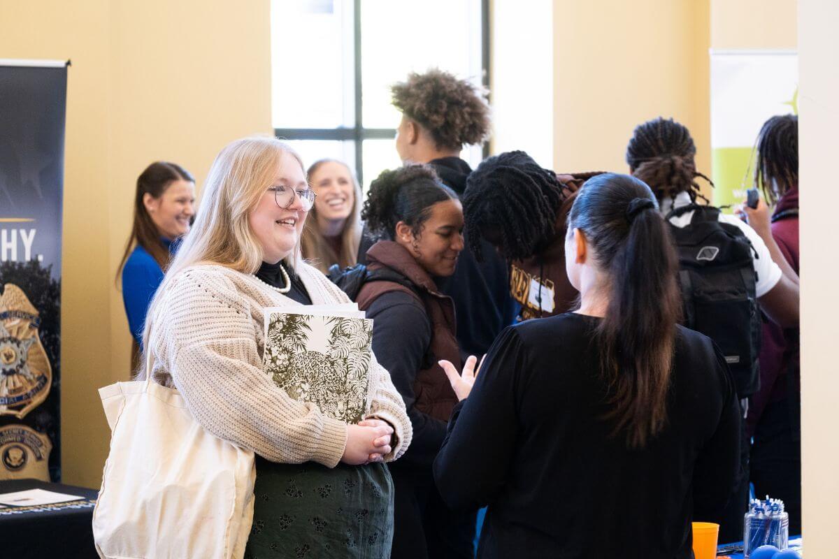 Photo of a smiling student talking to a potential employer