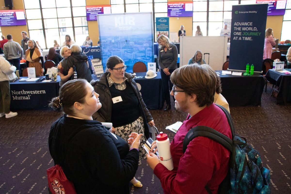 Photo of MC students standing in front of tables of representatives at the MC Career Fair