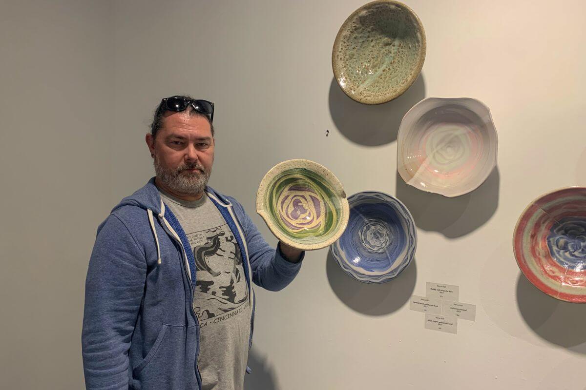 Photo of Barron Hall with his ceramics works on the wall