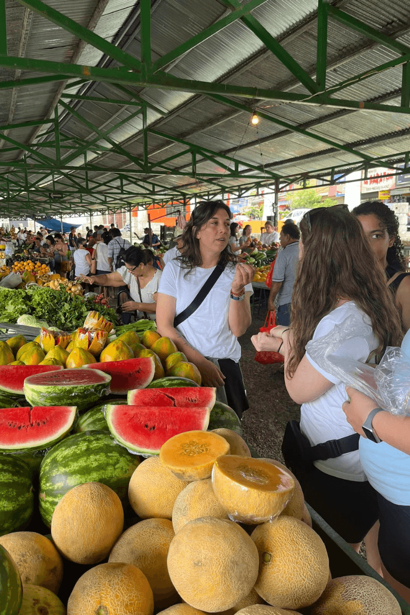 Dr. Oody and four MC students stand in front of a stall selling watermelon.