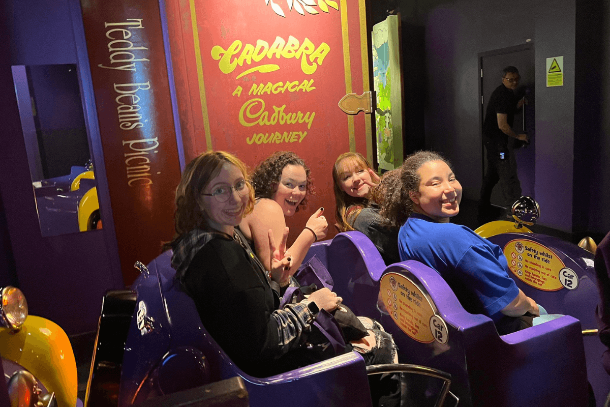 Four Maryville College students in a ride cart smiling.