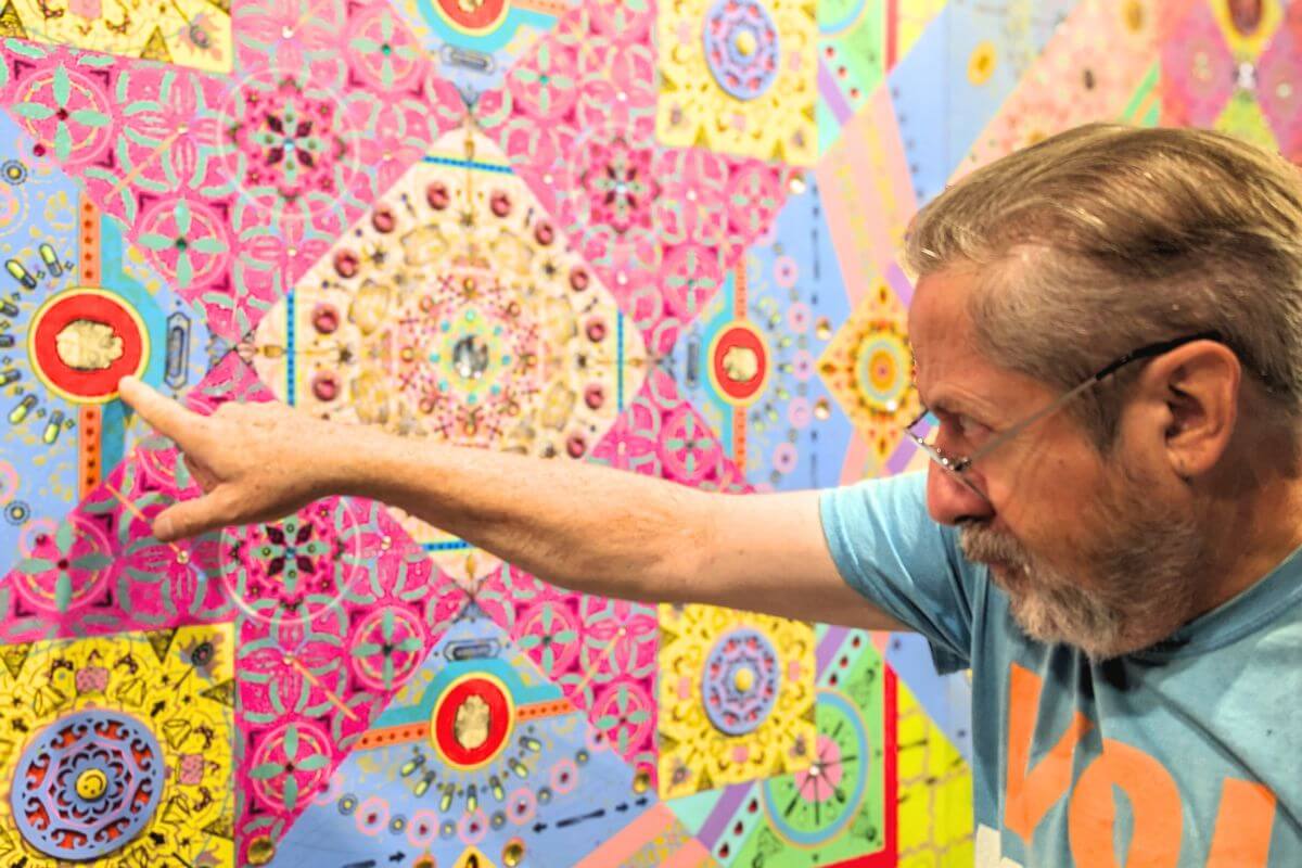 Photo of Dr. Carl Gombert pointing to a painting