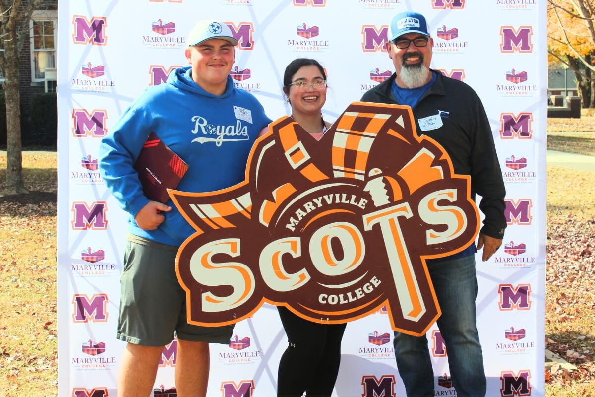 A family poses in front of a Maryville College backdrop during the November 2023 "Meet Maryville" event