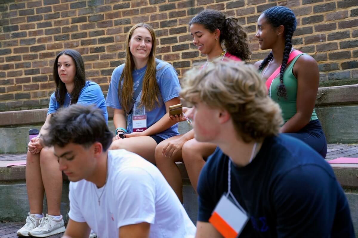 Photo of students sitting on concrete benches and smiling