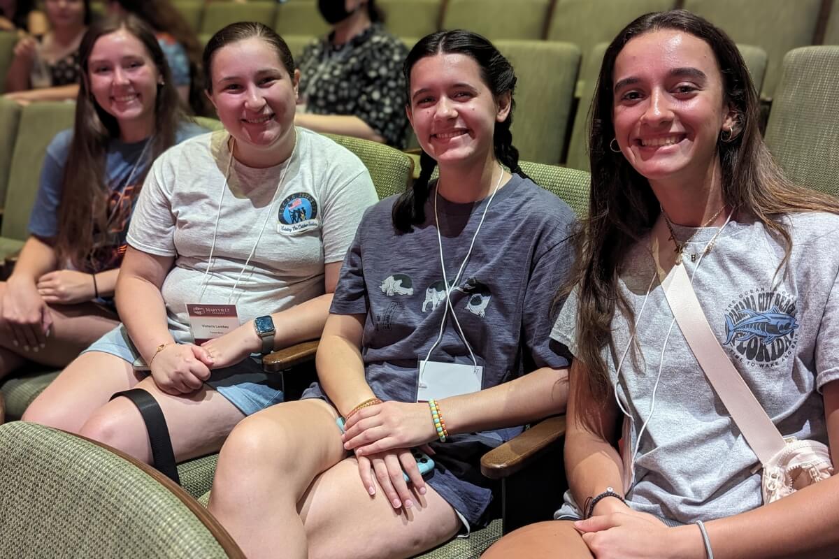 Photo of four smiling students in Lambert Recital Hall