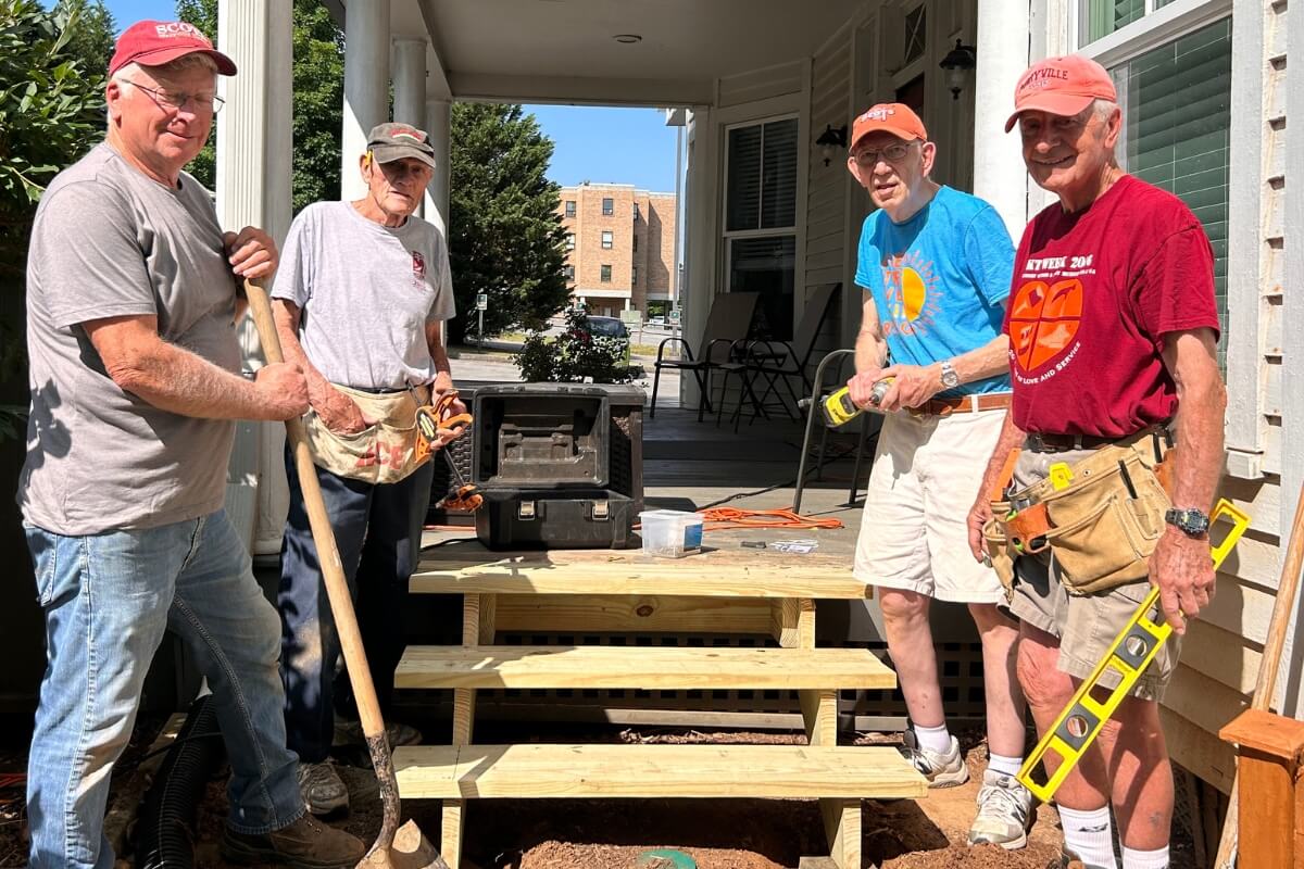 Photo of four Maryville College alumni beside a set of stairs constructed during KT Days 2023 on the Maryville College campus.