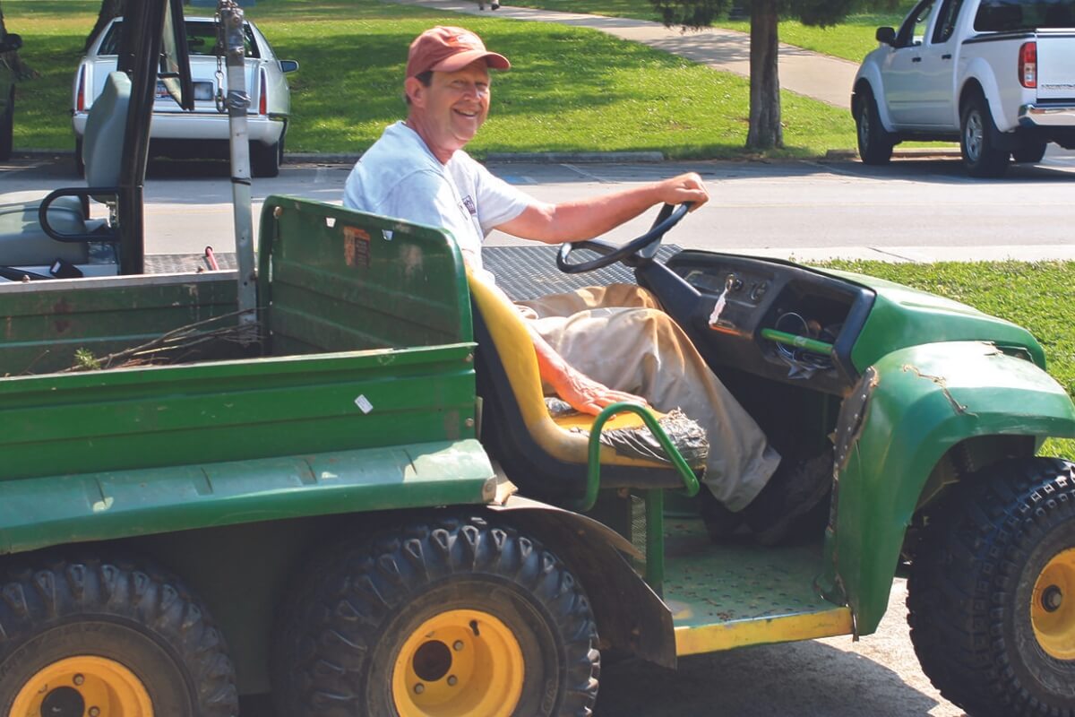 Photo of Tom Eberhard '60 driving a tractor and smiling and waving at the camera