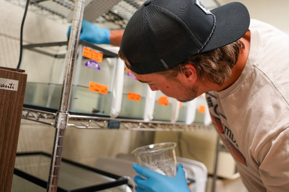 Photo of Christian Carlton in a science lab taking a water sample