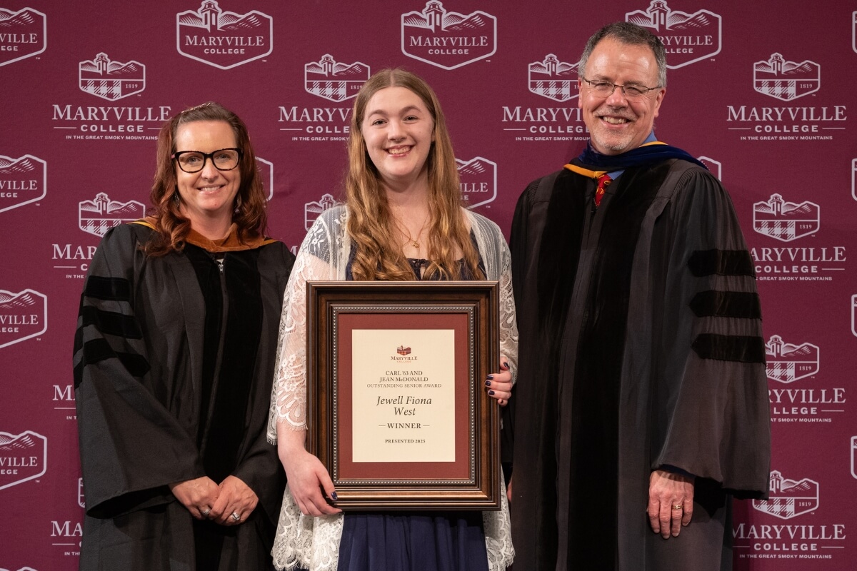 Photo of the Maryville College Outstanding Senior Award winner between two professors in academic robes