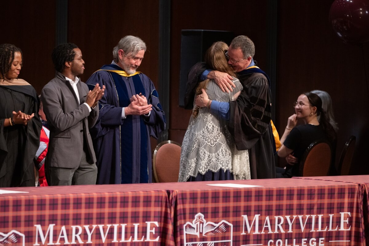 Photo of a professor hugging a student at an awards celebration