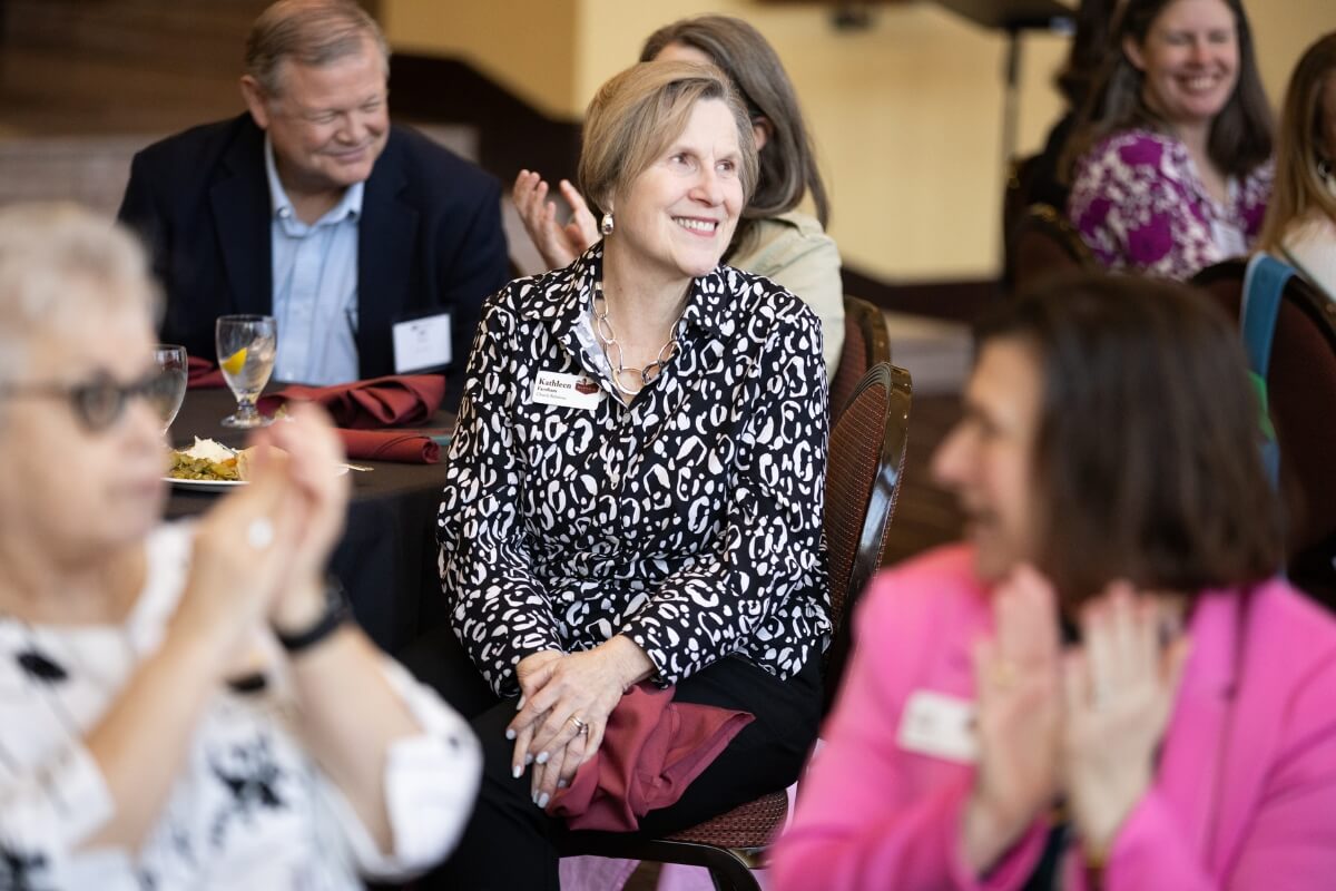 Photo of Kathleen Farnham smiling and surrounded by fellow banquet attendees