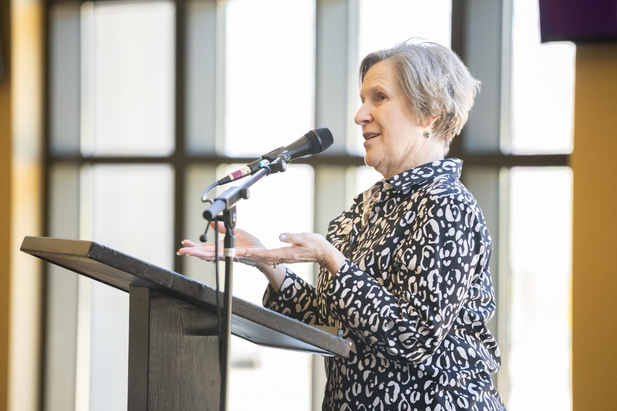 Photo of an elderly woman speaking into a microphone