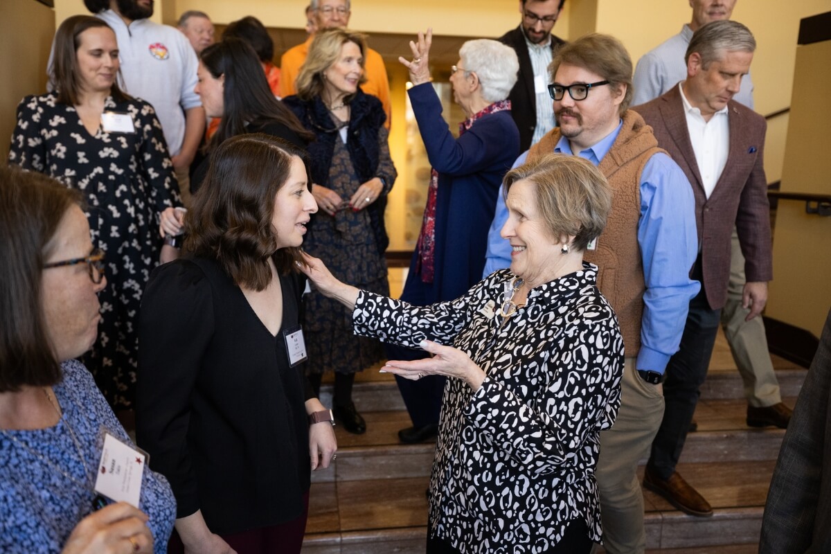 Photo of Kathleen Farnham greeting a woman wearing a black dress