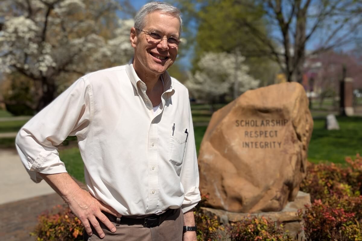 Photo of Dr. Sam Overstreet smiling and standing in front of the Maryville College Covenant Stone.