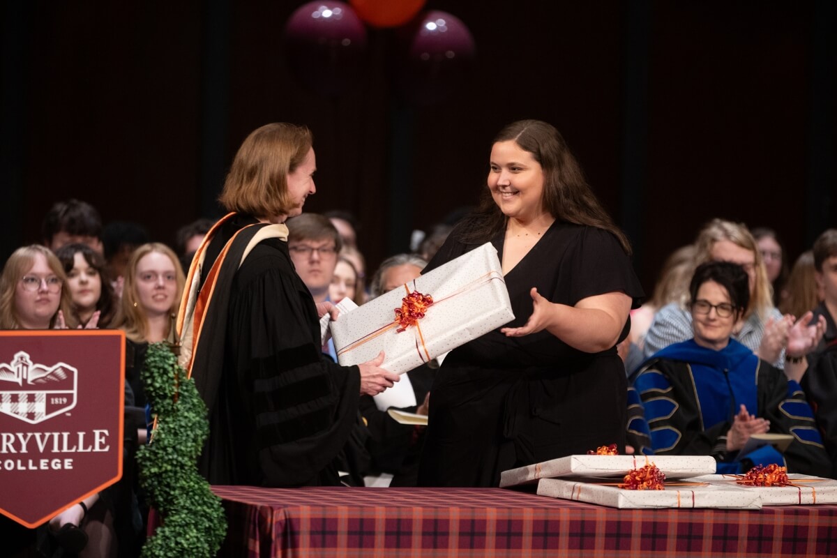 Photo of Dr. Jennifer Brigati handing a package to a student