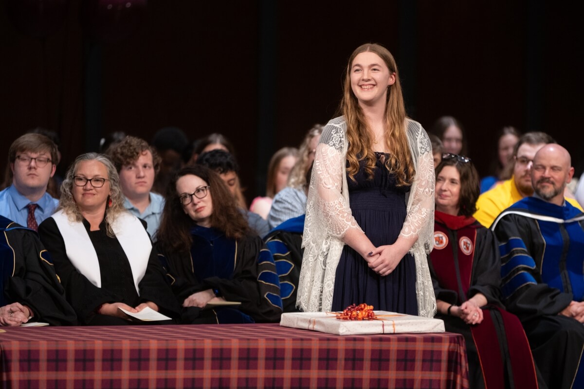 Photo of Jewell West listening to someone at a podium off-camera