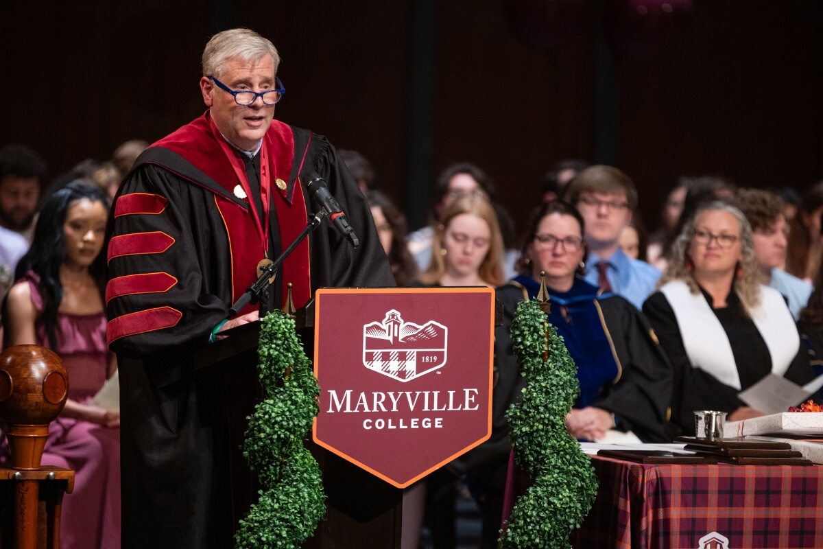Photo of Dr. Bryan Coker leaning over a lectern, speaking