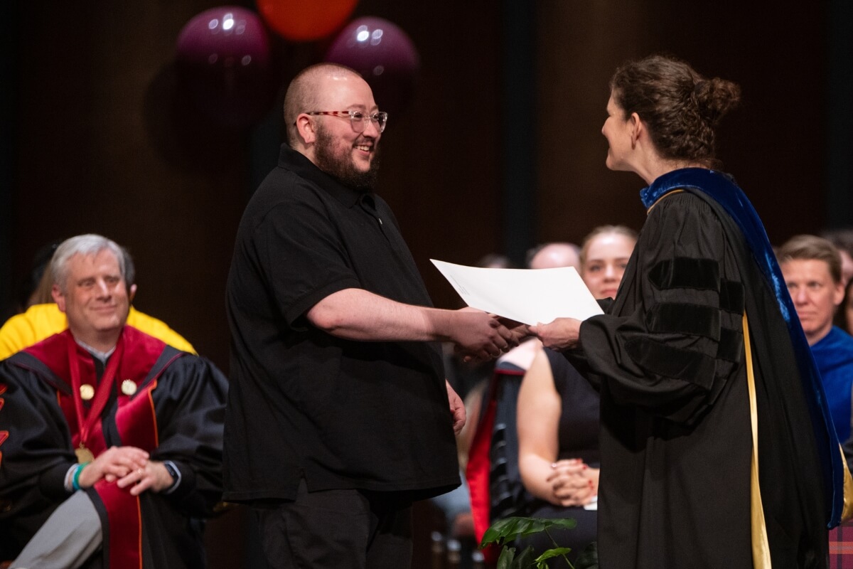 Photo of a student receiving an award from a professor
