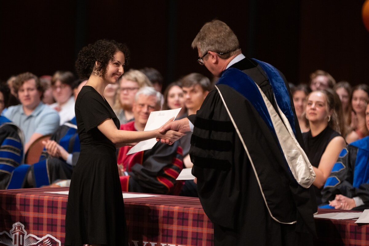 Photo of Dr. Will Phillips presenting an award to a student at a ceremony