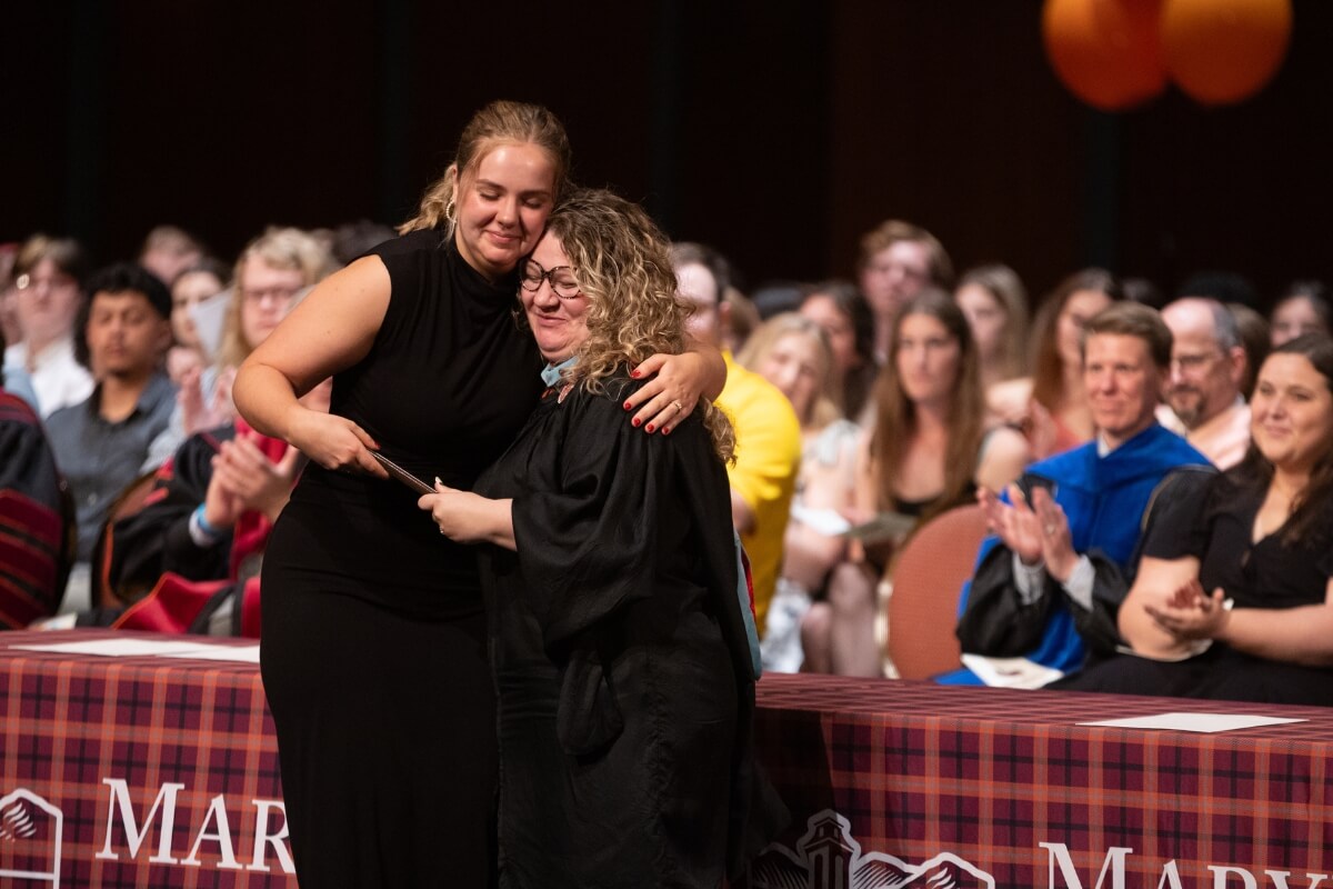 Photo of an Admissions staff member hugging a student at an awards ceremony