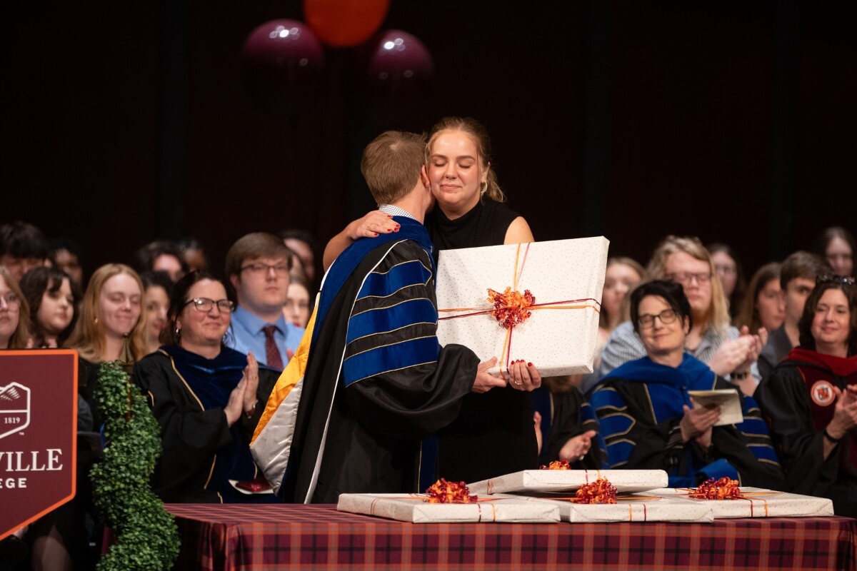 Photo of Dr. Rachel Ponder hugging a student holding a package