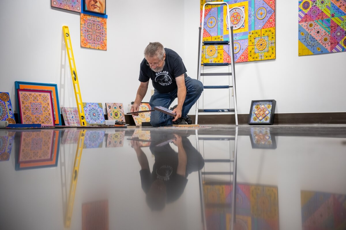 Photo of Dr. Carl Gombert kneeling and arranging works of art for display